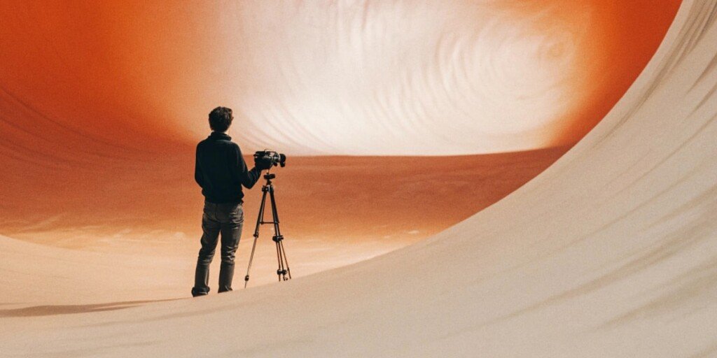 A silhouette of a filmmaker standing in a dark concrete room, watching the wall shatter to reveal a vibrant, swirling digital galaxy of colors and light.